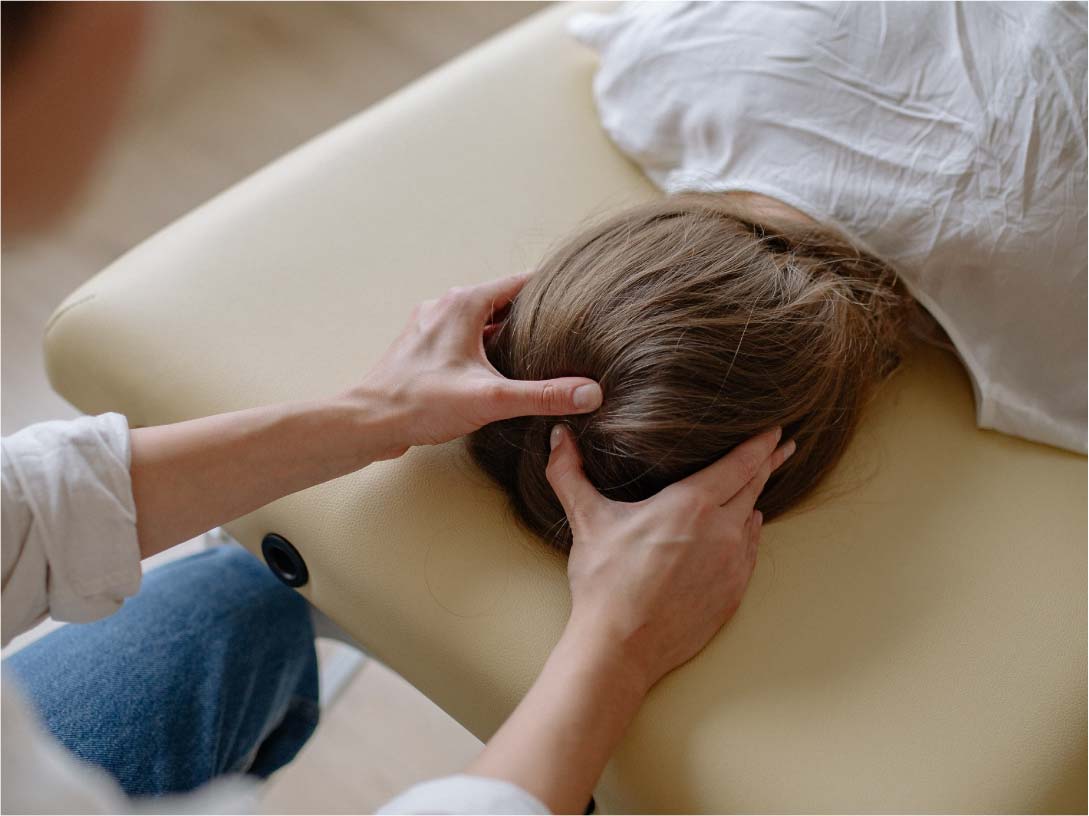 A woman getting craniosacral therapy on the back of their head